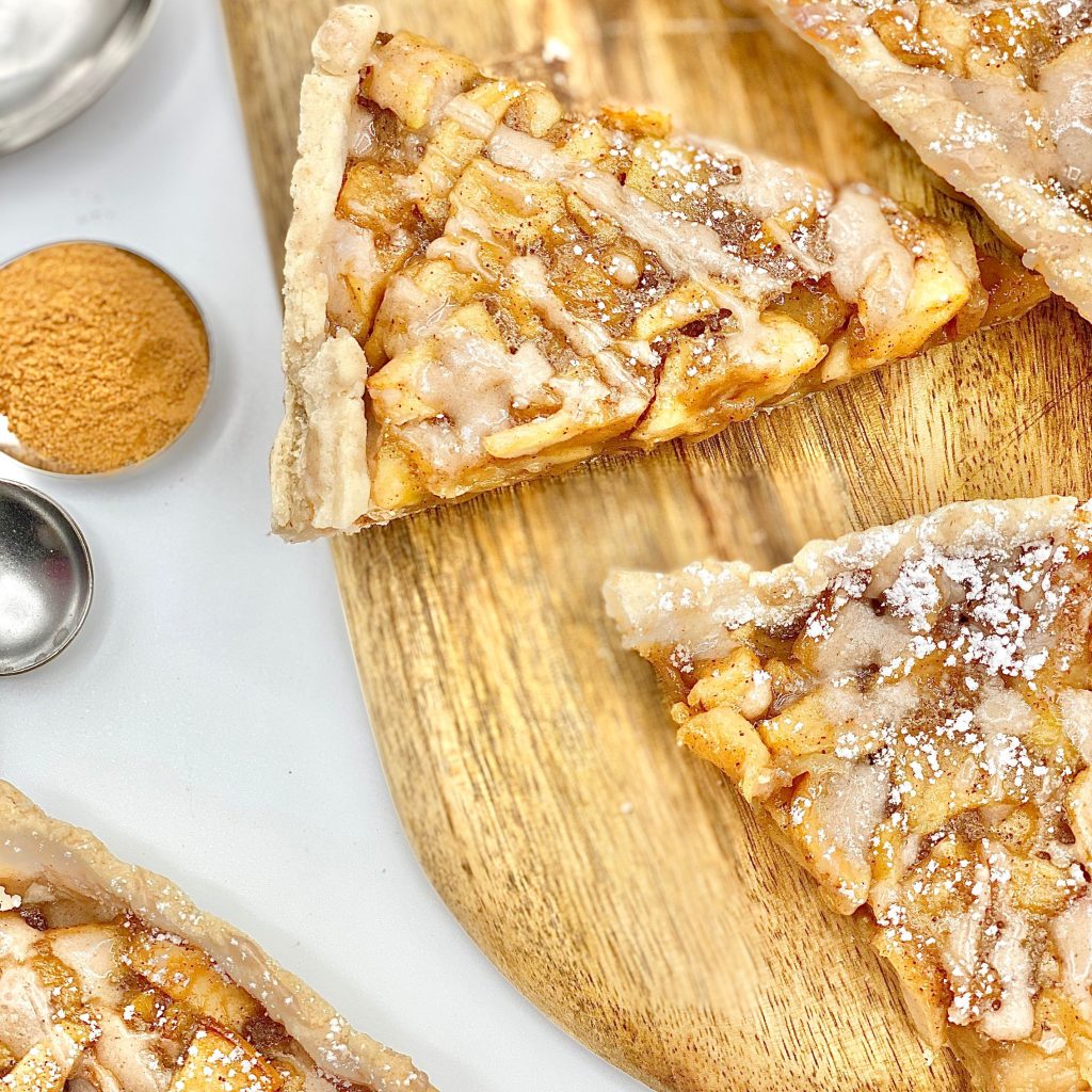 Slices of Apple Tart With Sugar Drizzle on a Wooden Board