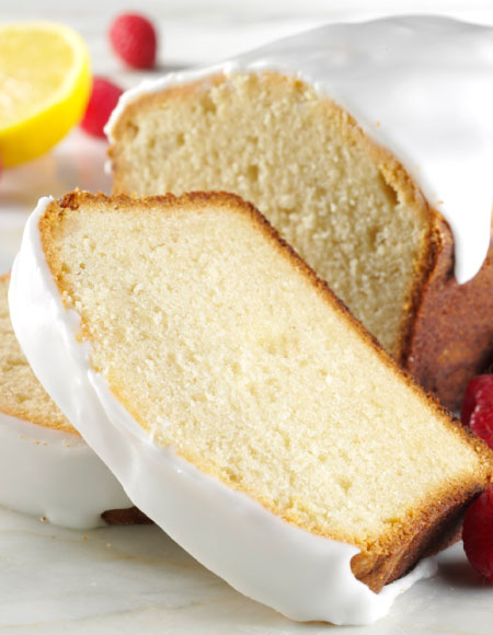 Pound Cake Loaf and Slices With White Icing in a Plate