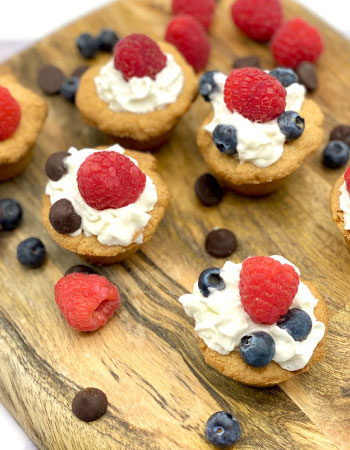 Cookies topped with cream, strawberries and blue berries